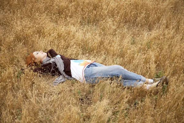 stock image Young beautiful girl lying at yellow autumn field.