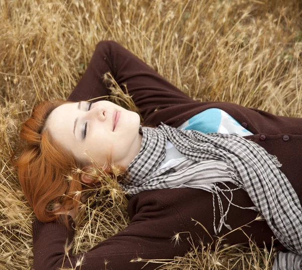 Young beautiful girl lying at yellow autumn field. — Stock Photo, Image