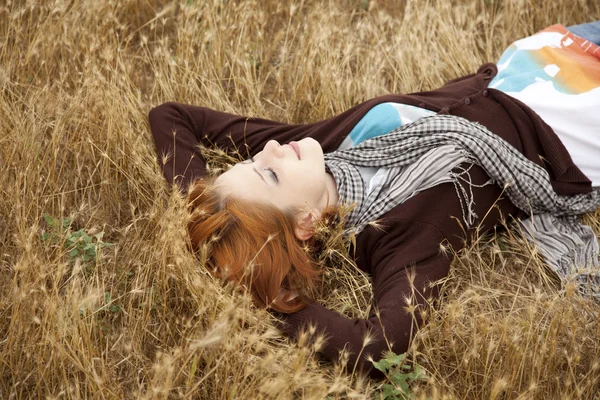 Junges schönes Mädchen liegt auf gelbem Herbstfeld. — Stockfoto