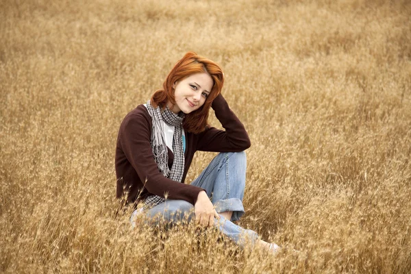 Vacker rödhårig flicka på gula höst gräset. — Stockfoto