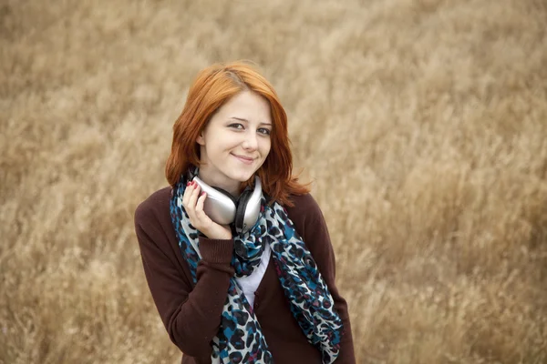 Moda sorridente jovem com fones de ouvido no campo . — Fotografia de Stock