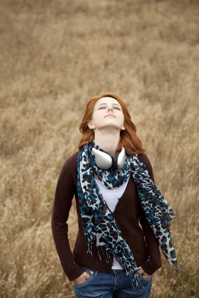 Jonge glimlachend mode met koptelefoon op veld. — Stockfoto