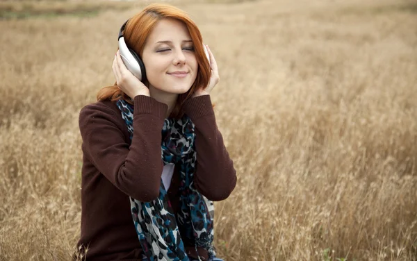 Jonge glimlachend mode met koptelefoon op veld. — Stockfoto