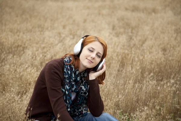 Junge lächelnde Mode mit Kopfhörern auf dem Feld. — Stockfoto
