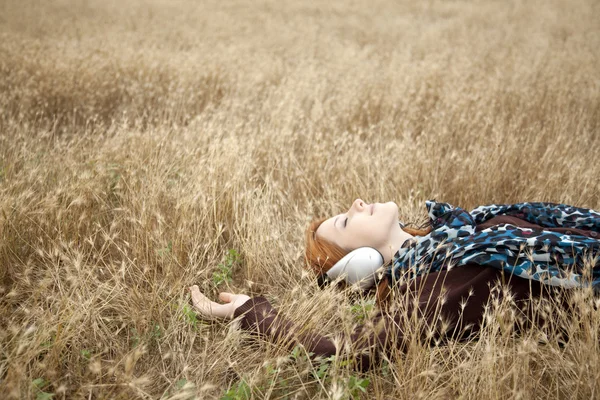 Unga leende mode med hörlurar liggande på fältet. — Stockfoto