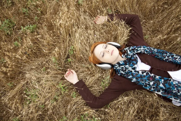 Молодая улыбающаяся мода с наушниками, лежащими на поле . — стоковое фото
