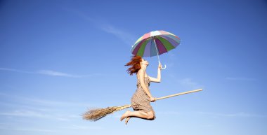 Young red-haired witch on broom flying in the sky with umbrella clipart