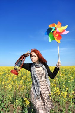 Young girl with wind turbine and retro lamp at rape field. clipart