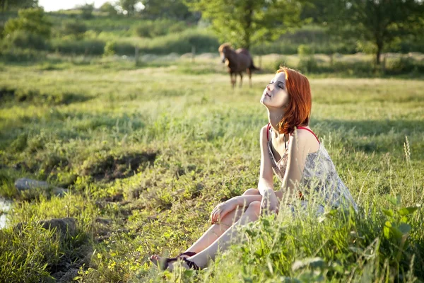 Meisje op het groene grasveld bij zonsondergang. — Stockfoto