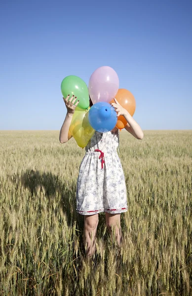 Meisje met ballonnen aan het tarweveld — Stockfoto