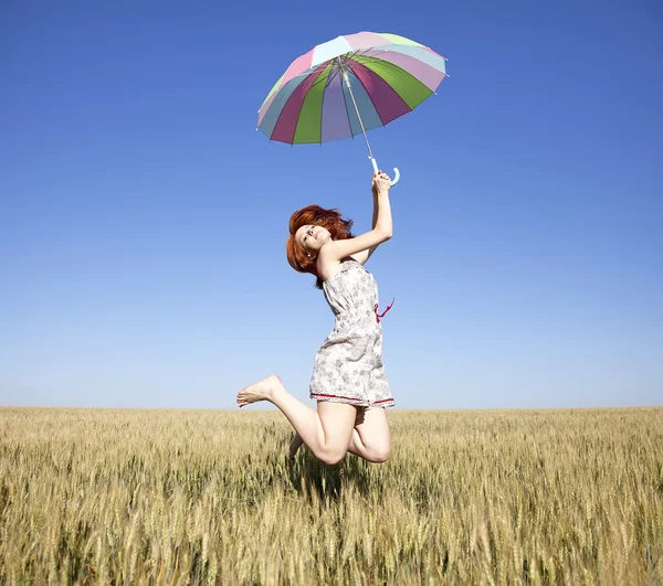 Прыгающая девушка с зонтиком на поле — стоковое фото