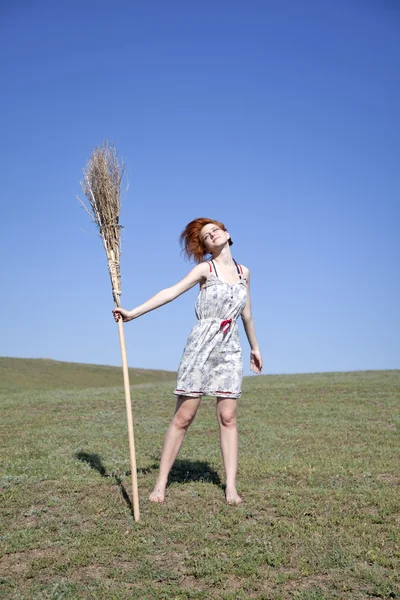 Jovem bruxa ruiva no campo de grama verde com vassoura — Fotografia de Stock
