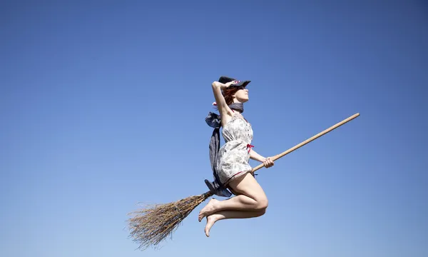Jovem bruxa ruiva na vassoura voando no céu — Fotografia de Stock