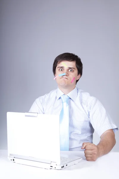 Joven jefe con portátil blanco y notas en la cara . — Foto de Stock