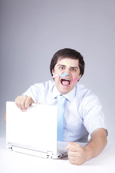 Jeune patron avec ordinateur portable blanc et notes sur le visage . — Photo