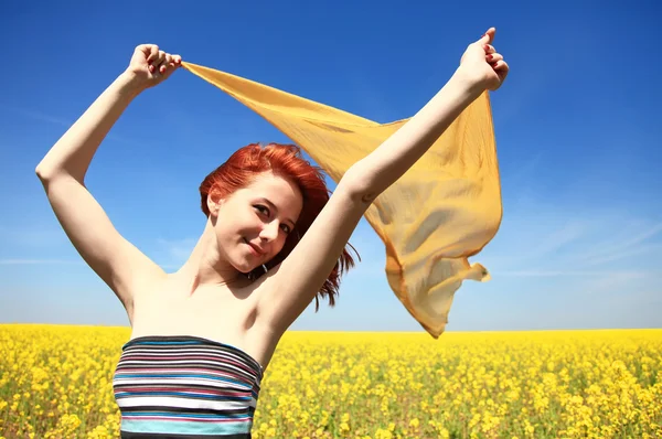 Mujer joven con los brazos abiertos mantener la seda amarilla en el viento en el campo de violación . — Foto de Stock