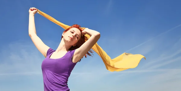 Молодая женщина с распростертыми объятьями держит желтый шелк на ветру . — стоковое фото