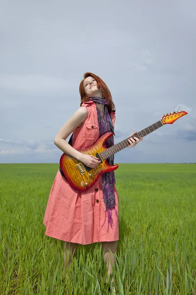 Девушка в платье на зеленом пшеничном поле с гитарой . — стоковое фото
