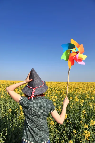 Молодая колдунья с ветряной турбиной на поле рапса . — стоковое фото