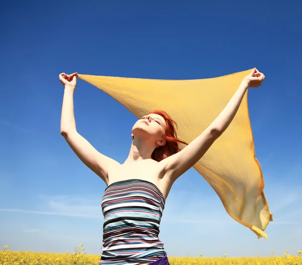 Молода жінка з відкритими руками тримає жовтий шовк на вітрі на полі зґвалтування . — стокове фото