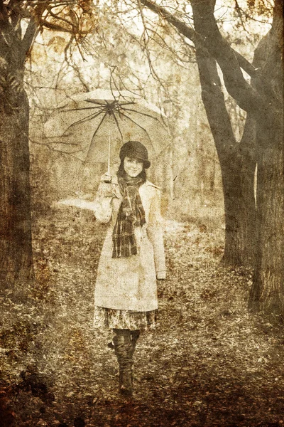 Mädchen mit Regenschirm im Park bei Regen. Foto im Vintage-Stil — Stockfoto