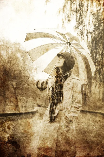Dívka s deštníkem v parku v deštivý den. Foto v retro stylu — Stock fotografie