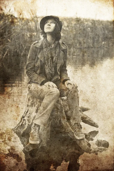 Menina sentada no toco na água. Foto em estilo vintage . — Fotografia de Stock