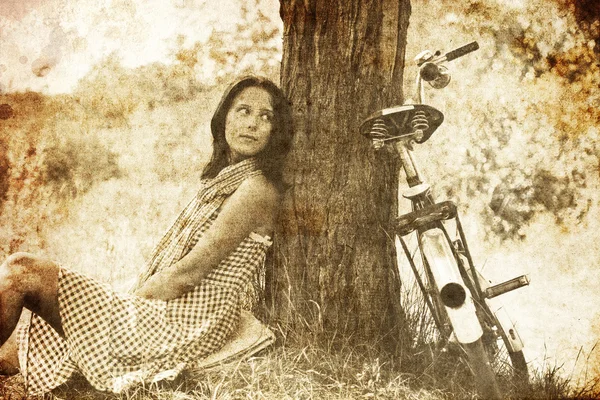 Piękna dziewczyna siedzi w pobliżu rower i drzewa w stanie spoczynku w lesie. Fotografia w starych i — Zdjęcie stockowe