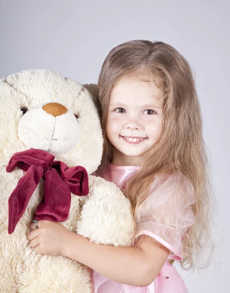 Kleines Mädchen umarmt Bärenjunges. — Stockfoto
