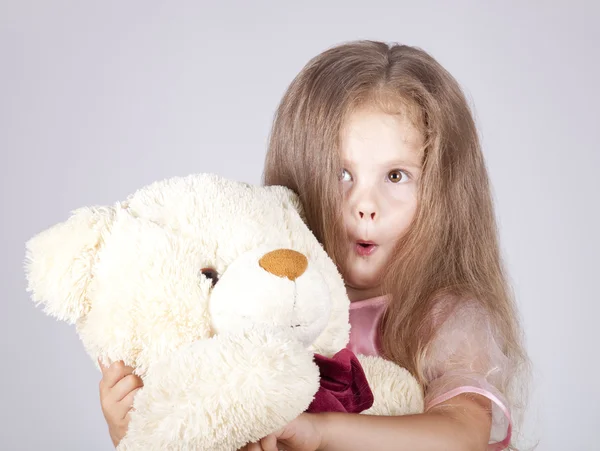 Lilla undrar flickan omfamnar björnen cub. — Stockfoto