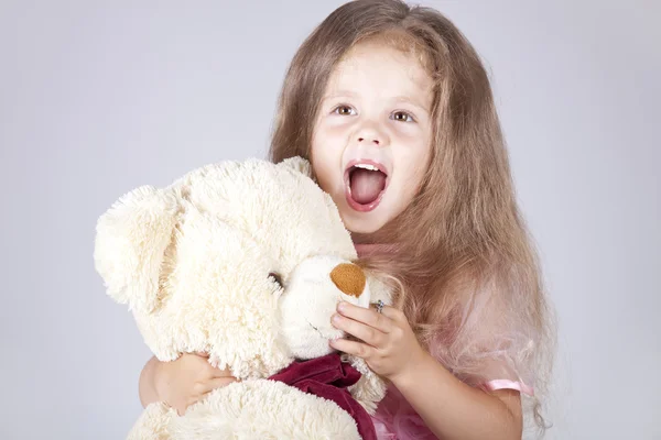 Kleines schreiendes Mädchen umarmt Bärenjunges. — Stockfoto