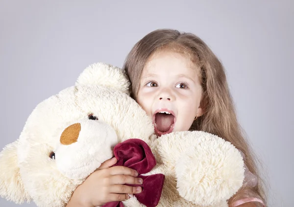 Kleines schreiendes Mädchen umarmt Bärenjunges. — Stockfoto