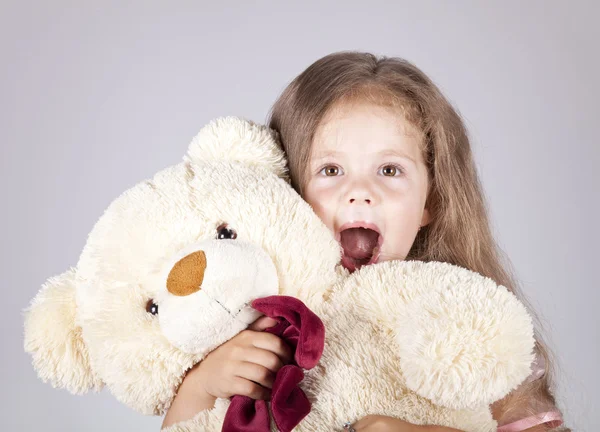 Маленькая кричащая девочка обнимает медвежонка . — стоковое фото