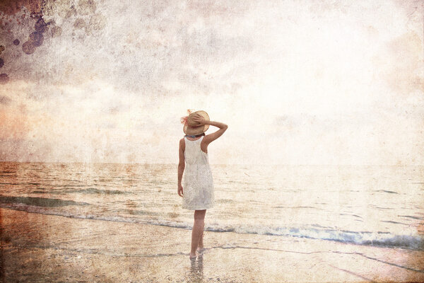 Young beautiful girl on the beach at sunrise. Photo in old colour image style.