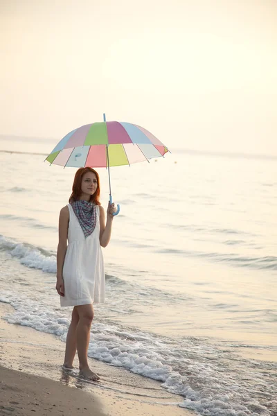 Giovane bella ragazza sulla spiaggia all'alba con ombrellone . — Foto Stock
