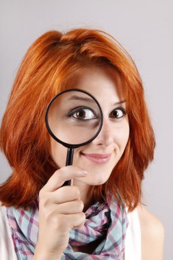 Beautiful red-haired girl with loupe zooming her eye clipart