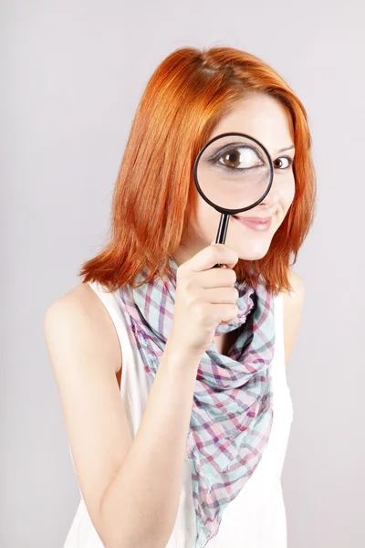 漂亮的红发女孩用放大镜放大她的眼睛 — 图库照片