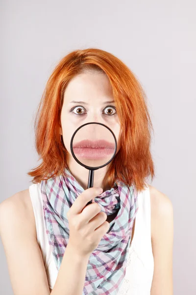 Beautiful red-haired girl with loupe zooming her mouth. — Stock Photo, Image