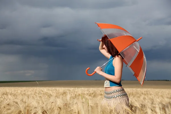 Meisje met paraplu op field in regenachtige dag. — Stockfoto