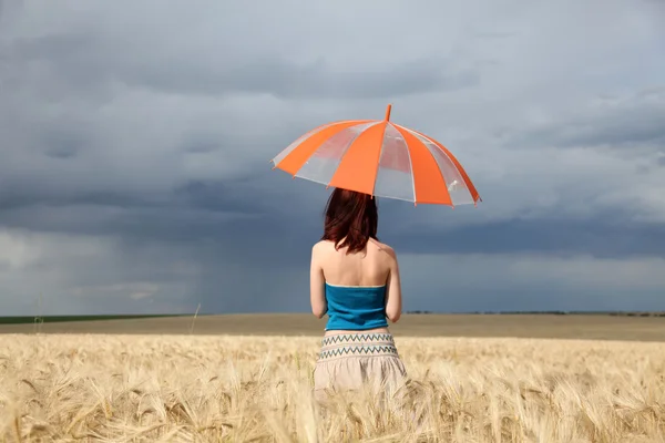 Mädchen mit Regenschirm auf Feld bei Regen. — Stockfoto