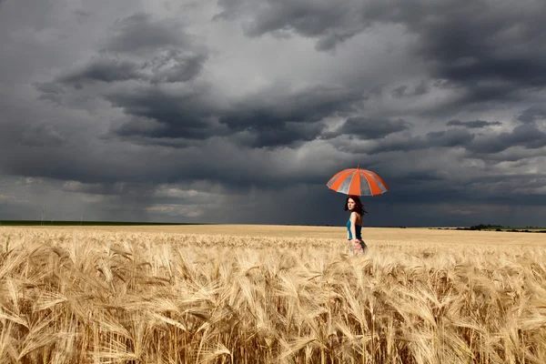 Meisje met paraplu op field in regenachtige dag. — Stockfoto