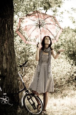 Bisiklet ve orman içinde kalan ağaca yakın güzel bir kız. retro fotoğraf