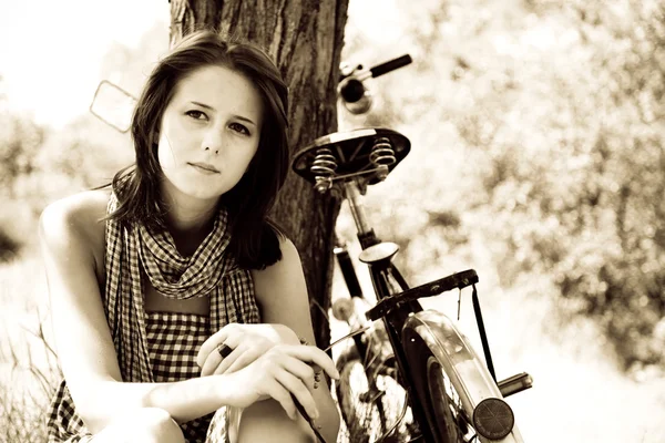 Piękna dziewczyna siedzi w pobliżu rower i drzewa w stanie spoczynku w lesie. zdjęcie w stylu retro — Zdjęcie stockowe