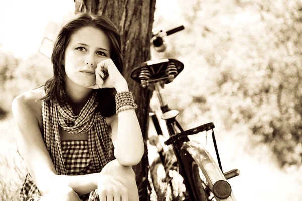 Belle fille assise près du vélo et de l'arbre au repos dans la forêt. Photo en rétro — Photo
