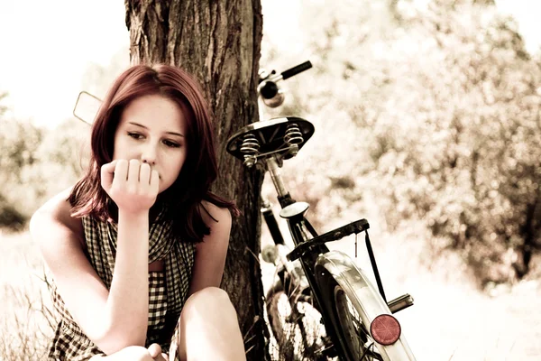 Vacker flicka sitter nära cykel och träd i vila i skogen. Foto i retro — Stockfoto