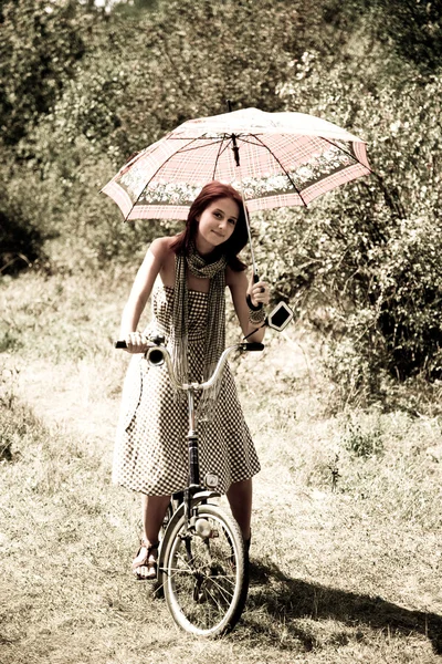 Όμορφο κορίτσι κοντά ποδήλατο και δέντρο σε ανάπαυση στο δάσος. φωτογραφία σε ρετρό — 图库照片