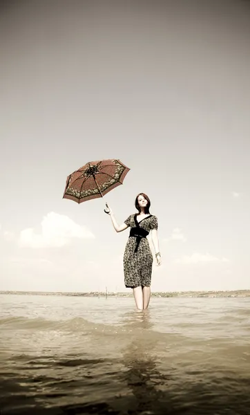 Girl at water with umbrella in hand. — Stock Photo, Image