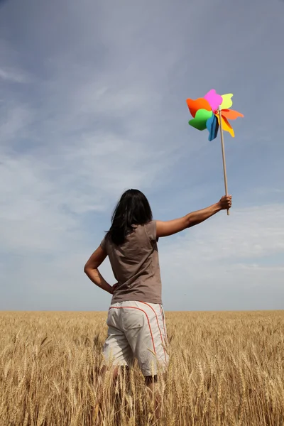 Dívka s větrnou turbínou na pšeničném poli — Stock fotografie