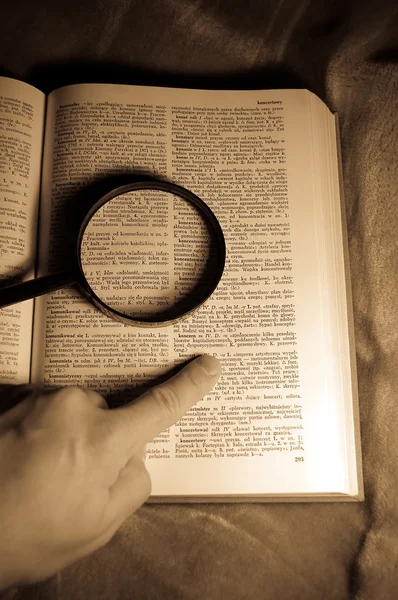 Investigation loupe at book and poiting hand — Stock Photo, Image