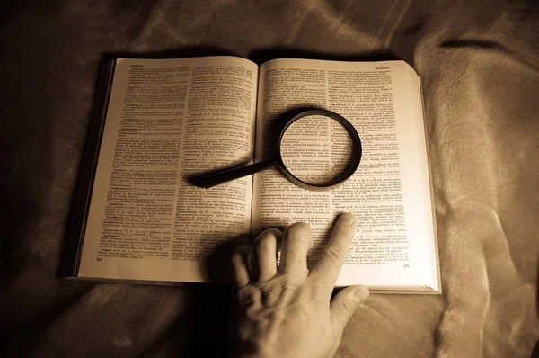 Расследование Лупа на книгу и poiting руки — стоковое фото